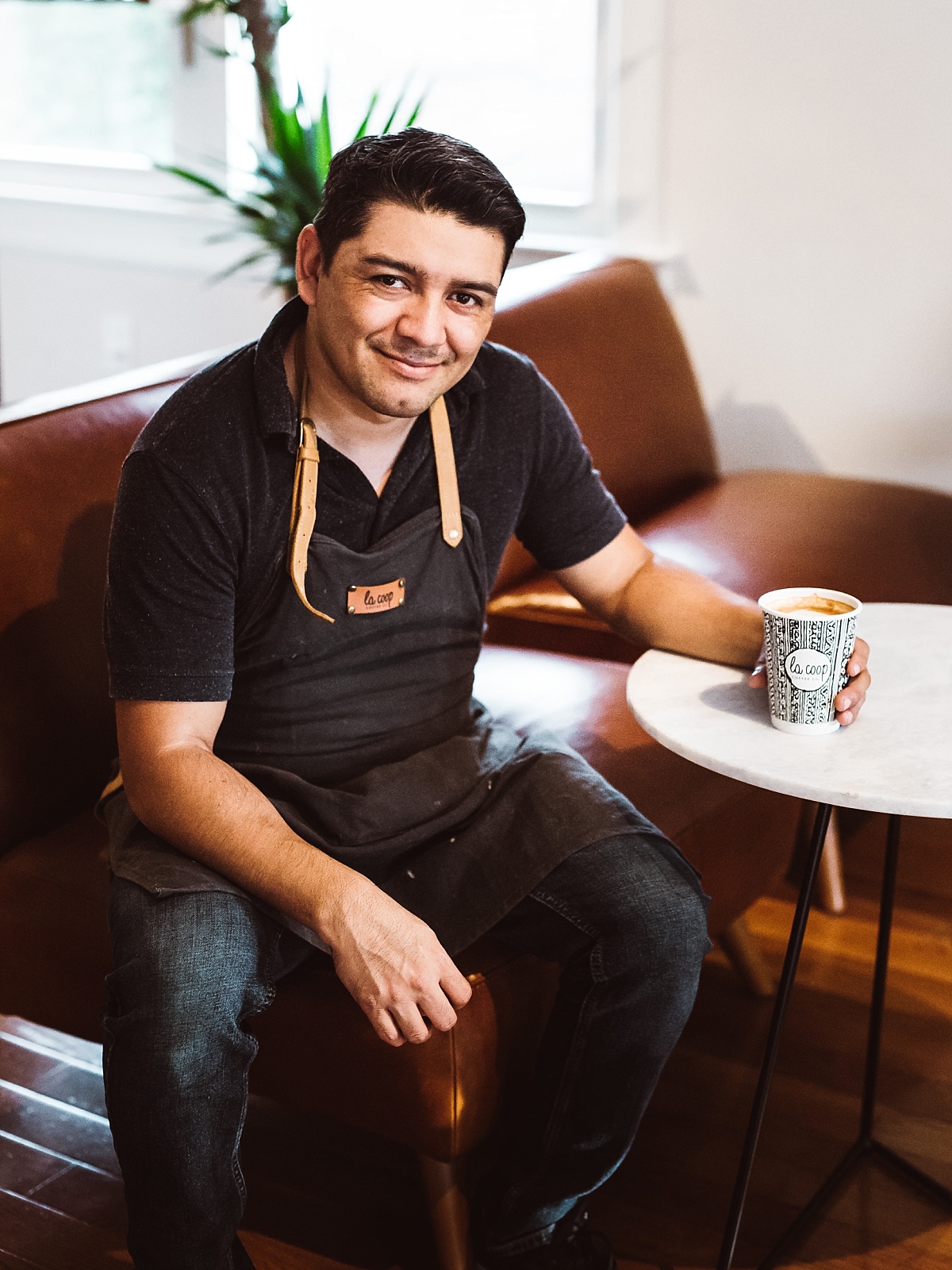 juan luis smiles at the camera in his DC coffee shop la coop coffee