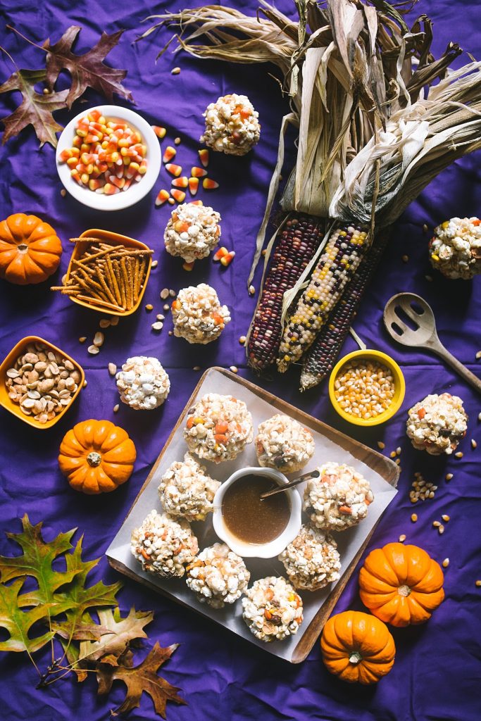 caramel popcorn balls and mini pumpkins on purple background
