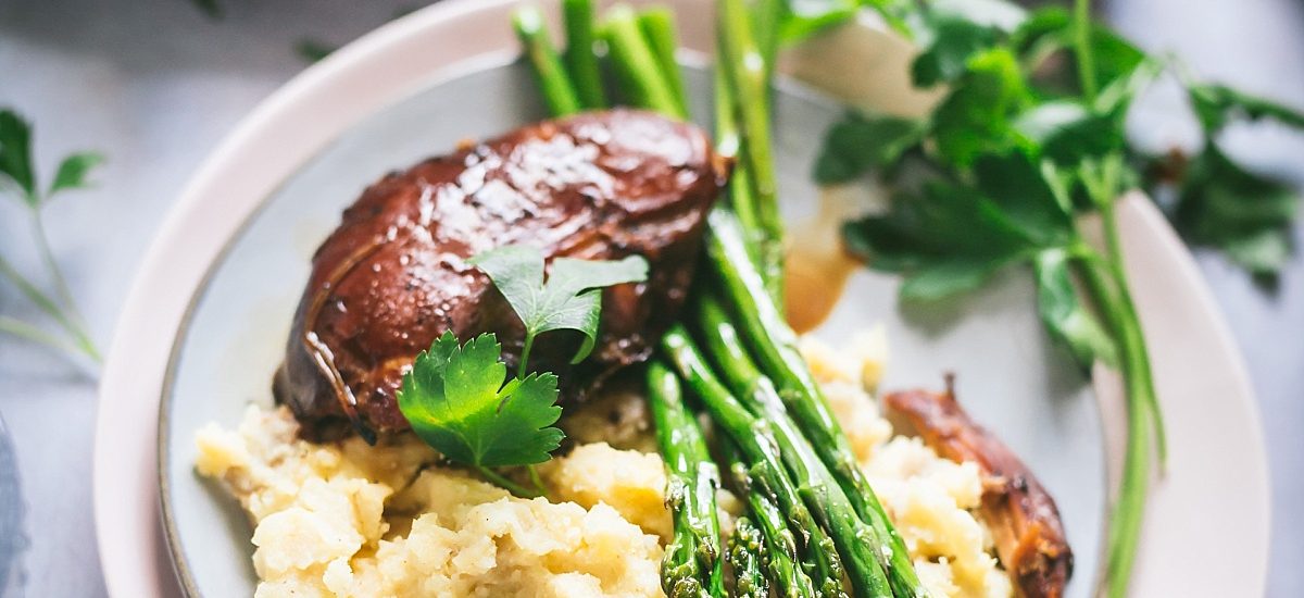 Balsamic Chicken Thighs Mashed potatoes and asparagus on pink and gray layered plates