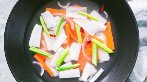 Dongchimi overhead shot of Korean radish sticks, carrots, green onions in fermented white kimchi broth
