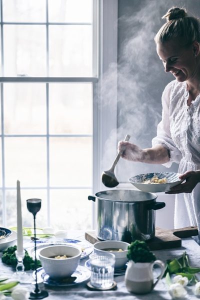 woman smiles serving chicken noodle soup with steam swirling around