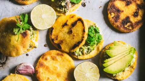 golden venezuelan arepas are tossed on a pan and topped with creamy chicken and avocado filling
