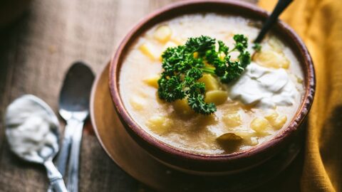 simple golden hungarian potato soup garnished with parsley and a dollop of sour cream