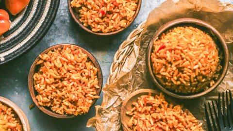 small brown wooden bowls and woven black and white african bowls hold Nigerian jollof rice