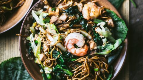 succulent shrimp topping a plate of Indonesian chicken mie goreng featuring asian greens