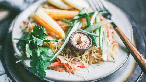 mushroom, baby corn, cilantro, and spring onions garnish a small plate of chicken pancit