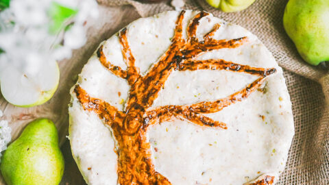 decorative pie features bare pear tree surrounded by pears and pistachios to suggest filling