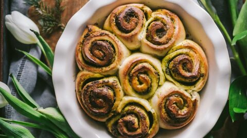 golden spirals of soft dough filled with basil pesto fill a pie plate over cutting board