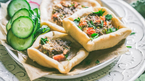 Lebanese safiha in square shape with fresh ground lamb, diced tomatoes and green pepper piled on a plate