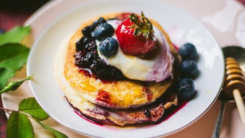fluffy Polish sweet omelette on a dish stacked like pancakes with fresh cream, blueberries, and strawberry