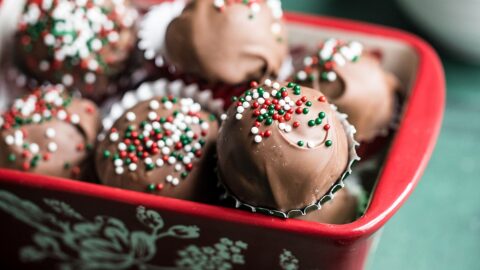 adorable red mini ceramic loaf pan overflowing with Christmas truffles decorated with red white green nonpareils