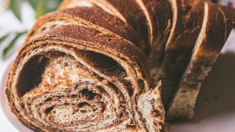 closeup shot of sliced loaf of spiraled povitica bread with walnut cinnamon swirl on a pink plate